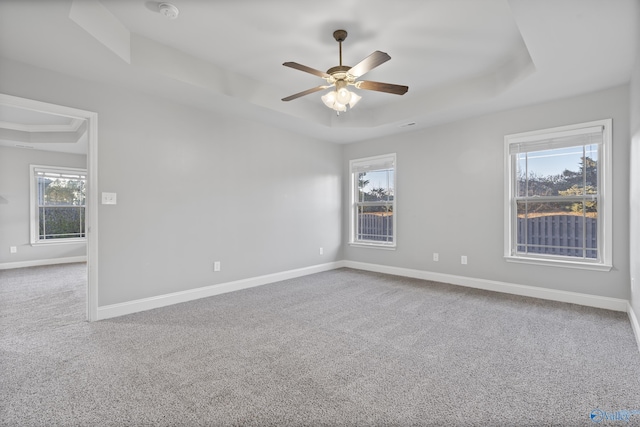 carpeted spare room featuring ceiling fan and a tray ceiling