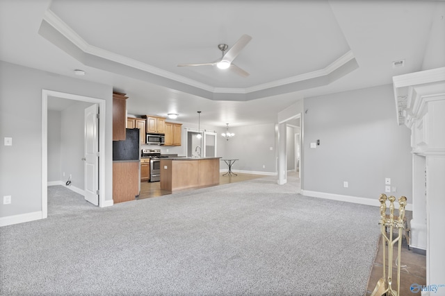 kitchen with appliances with stainless steel finishes, decorative light fixtures, a raised ceiling, and a kitchen island