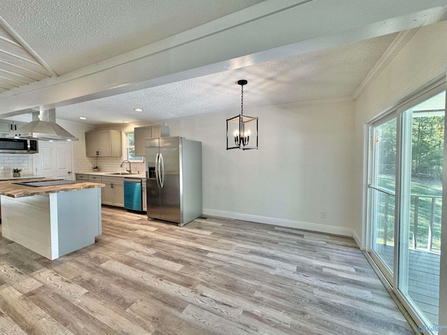 kitchen featuring appliances with stainless steel finishes, butcher block countertops, backsplash, light hardwood / wood-style floors, and pendant lighting