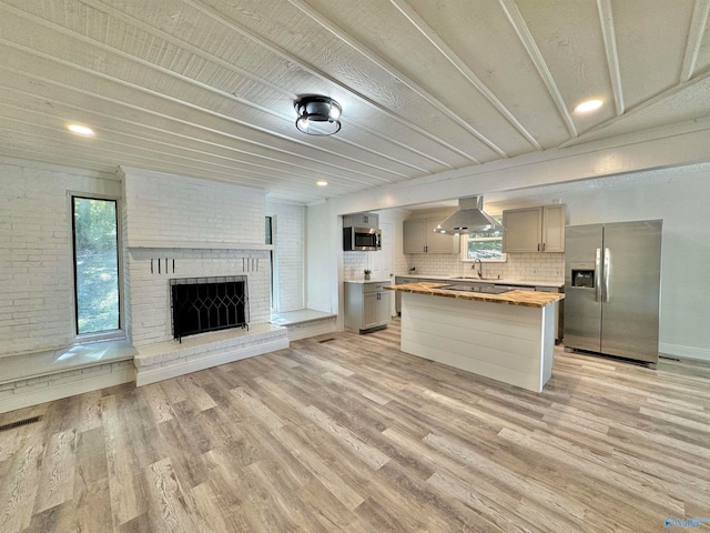 kitchen featuring light hardwood / wood-style flooring, stainless steel appliances, range hood, and wood counters