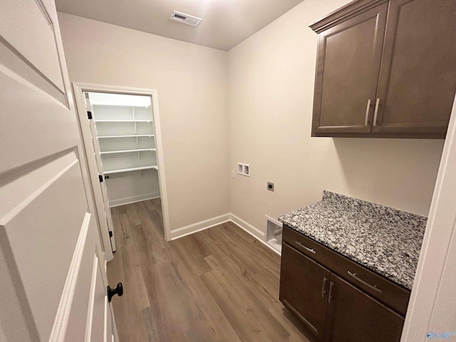 clothes washing area featuring cabinets, washer hookup, hardwood / wood-style floors, and electric dryer hookup