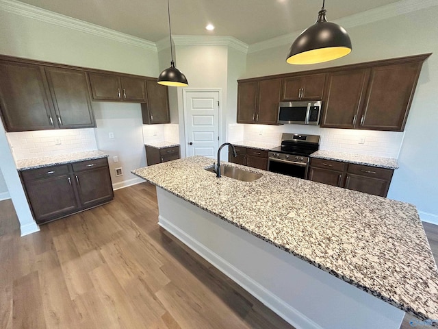 kitchen with light stone countertops, appliances with stainless steel finishes, sink, and decorative light fixtures