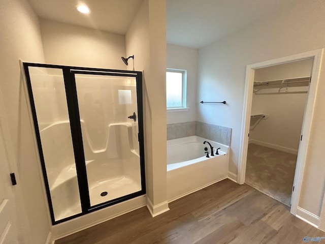 24081 Quints Dr, Athens, AL 35613 - bathroom featuring a shower stall, wood finished floors, a bath, a spacious closet, and baseboards