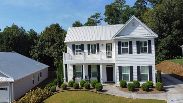 view of front facade featuring a balcony, a front yard, and covered porch