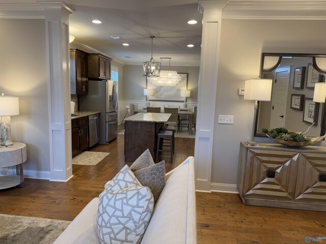 kitchen with sink, light stone counters, a kitchen island, pendant lighting, and stainless steel appliances