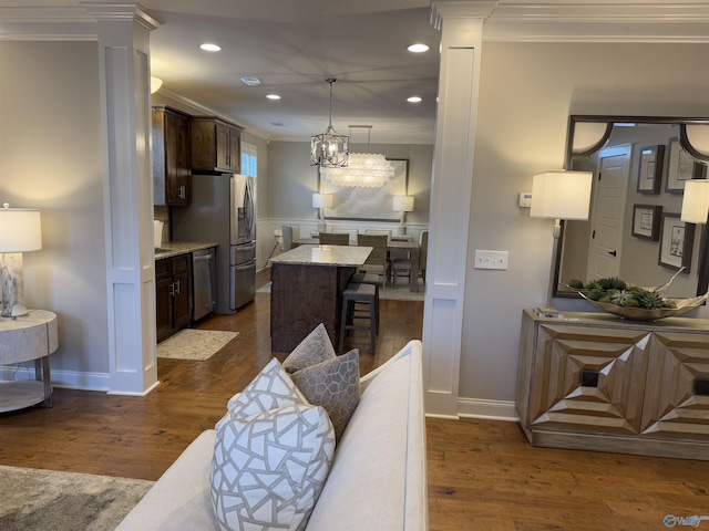 kitchen featuring stainless steel appliances, dark wood-type flooring, crown molding, and a kitchen breakfast bar