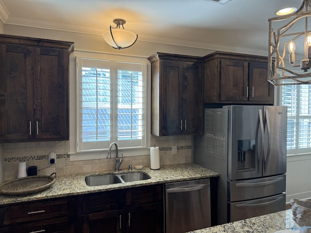 kitchen featuring appliances with stainless steel finishes, ornamental molding, a sink, dark brown cabinets, and backsplash