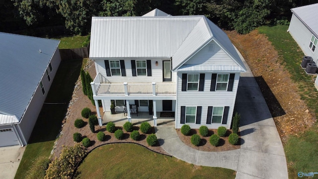 view of front facade with central AC, metal roof, a patio, and a balcony