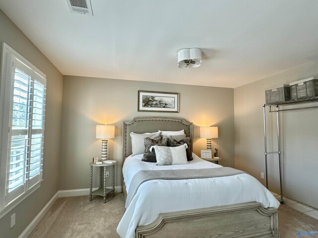 bedroom featuring light colored carpet and multiple windows