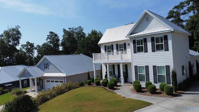 view of front facade featuring a garage, a balcony, metal roof, a porch, and a front yard