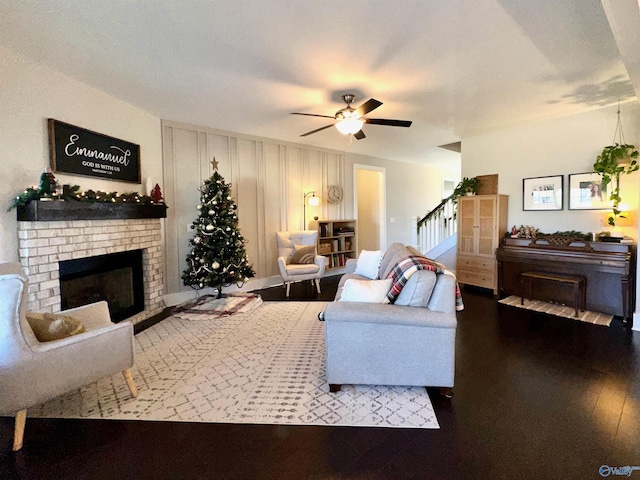 living room featuring hardwood / wood-style flooring, ceiling fan, and a fireplace