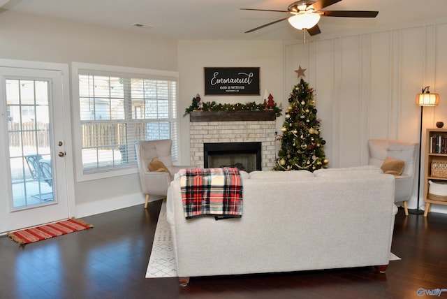 living room with ceiling fan, dark wood-type flooring, and a brick fireplace