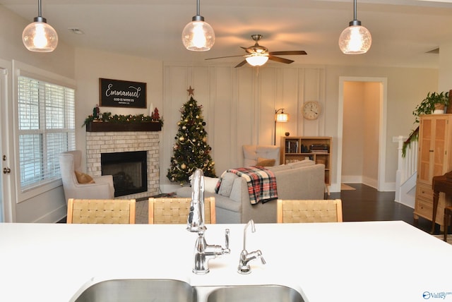 kitchen featuring ceiling fan, a fireplace, wood-type flooring, and decorative light fixtures