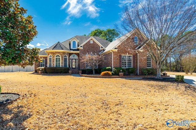 view of front facade with fence and brick siding