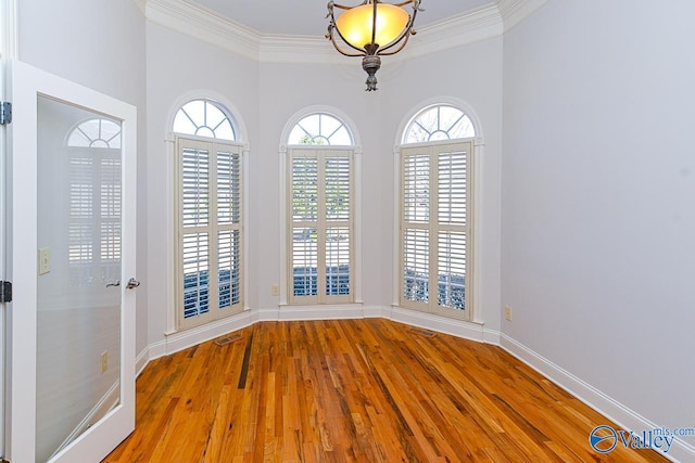 spare room featuring baseboards, crown molding, visible vents, and wood finished floors