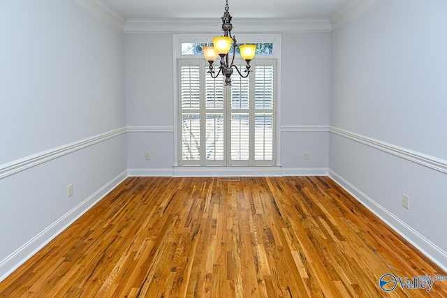 unfurnished room with a chandelier, ornamental molding, wood finished floors, and baseboards