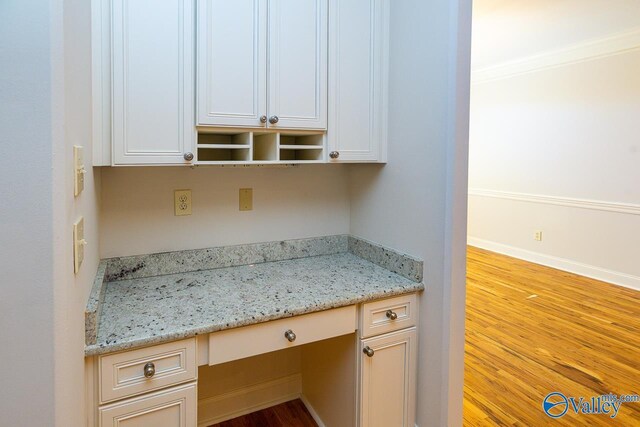 interior details featuring baseboards, ornamental molding, wood finished floors, and built in study area