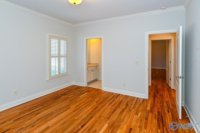 unfurnished bedroom with ornamental molding, ensuite bath, light wood-style flooring, and baseboards