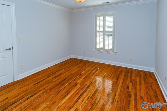 spare room with wood-type flooring, baseboards, and crown molding