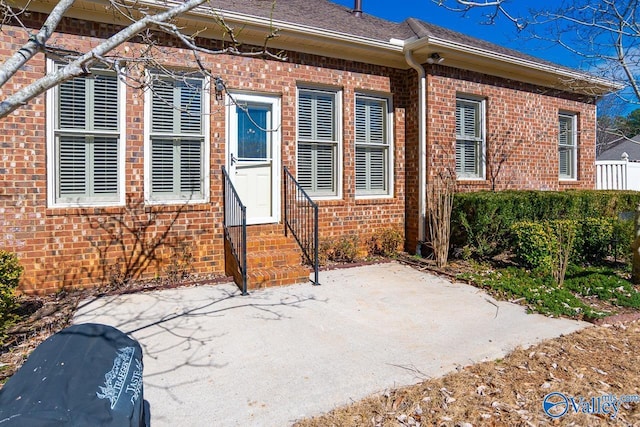 view of front of property with entry steps, roof with shingles, a patio, and brick siding