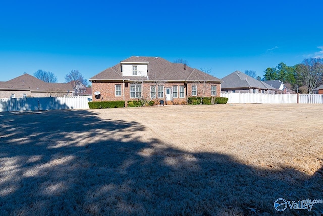 view of front of house with brick siding and a fenced backyard