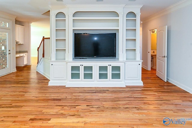 unfurnished living room featuring light wood-style flooring, baseboards, and crown molding