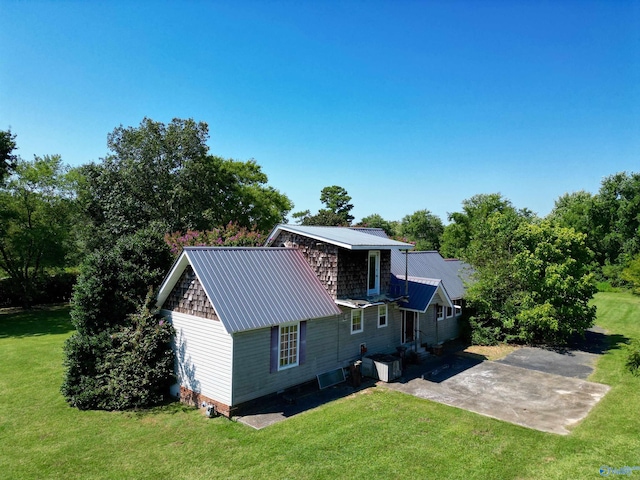 rear view of house featuring a patio area, a lawn, and metal roof