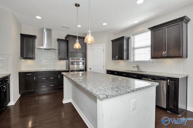 kitchen with stainless steel appliances, wall chimney exhaust hood, dark hardwood / wood-style floors, a kitchen island, and pendant lighting