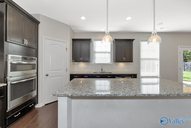 217 Skehan St SW, Huntsville, AL 35824 - kitchen featuring stainless steel double oven, dark wood-style flooring, light stone countertops, decorative backsplash, and recessed lighting