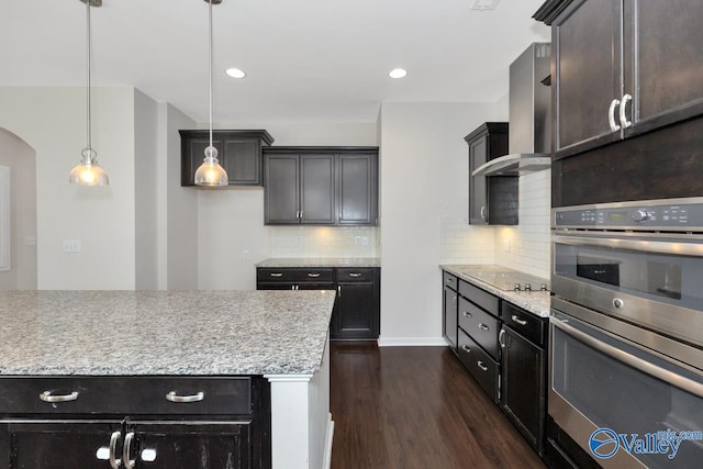 kitchen featuring tasteful backsplash, wall chimney range hood, decorative light fixtures, dark hardwood / wood-style flooring, and black electric cooktop