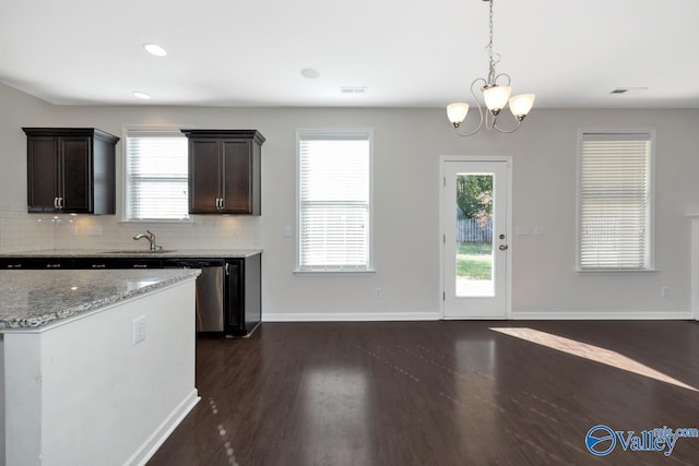 kitchen featuring tasteful backsplash, dark hardwood / wood-style floors, light stone countertops, hanging light fixtures, and sink