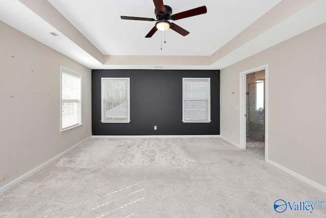 carpeted spare room featuring ceiling fan and a raised ceiling