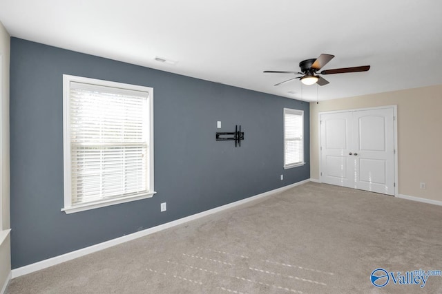 carpeted spare room featuring ceiling fan and plenty of natural light