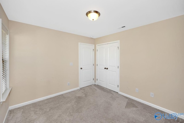 unfurnished bedroom featuring a closet and light colored carpet