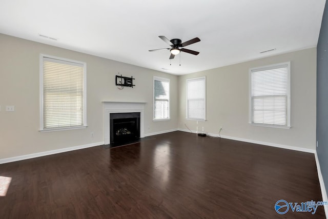 unfurnished living room with dark hardwood / wood-style flooring, a wealth of natural light, and ceiling fan