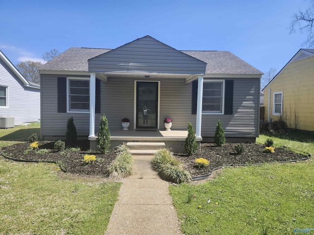 bungalow-style home featuring roof with shingles, a porch, central air condition unit, and a front lawn