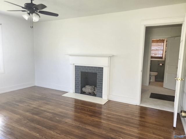 unfurnished living room featuring baseboards, a ceiling fan, wood finished floors, and a fireplace