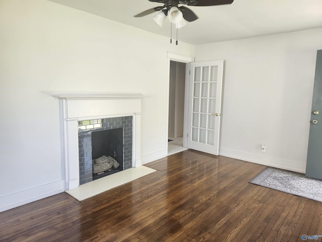unfurnished living room with a fireplace with raised hearth, baseboards, a ceiling fan, and wood finished floors