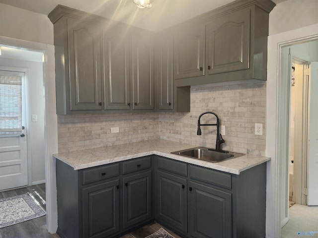 kitchen featuring wood finished floors, tasteful backsplash, a sink, and gray cabinets