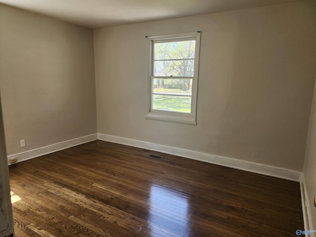 empty room with visible vents, baseboards, and dark wood finished floors