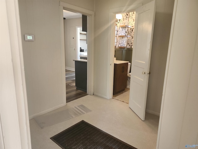 hallway with baseboards and light carpet