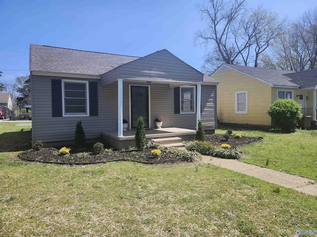 bungalow featuring a front yard, roof with shingles, and covered porch