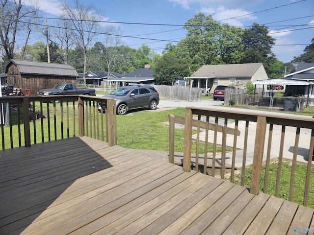wooden terrace with a yard, a residential view, an outdoor structure, and fence