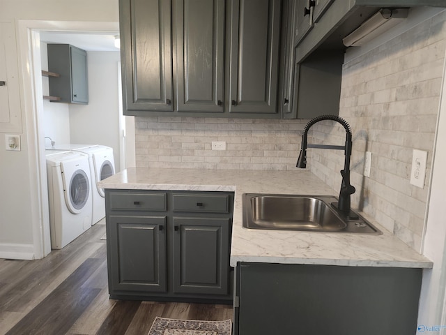 kitchen with independent washer and dryer, decorative backsplash, a sink, and dark wood finished floors