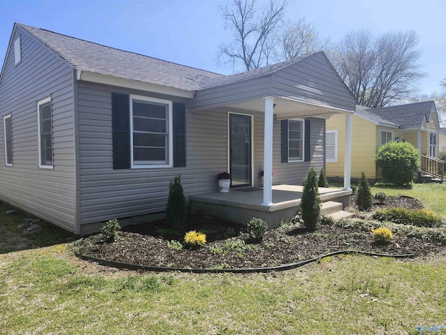 view of side of property with a shingled roof and covered porch
