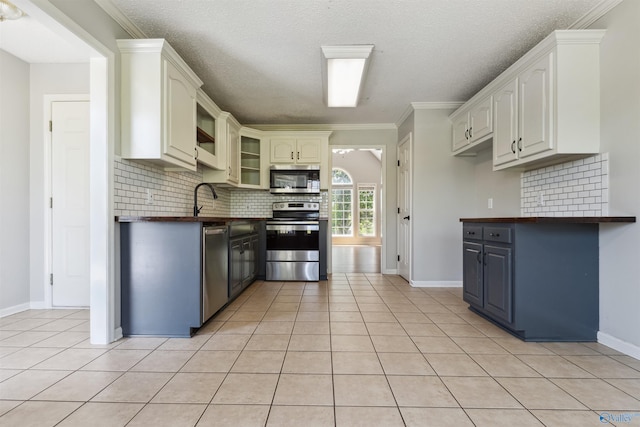 123 Turtle Ridge Dr, New Market, AL 35761 - kitchen with appliances with stainless steel finishes, backsplash, light tile patterned floors, baseboards, and a textured ceiling