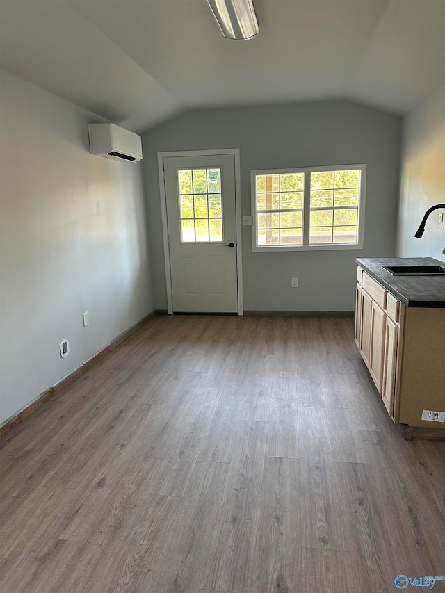 interior space with sink, lofted ceiling, hardwood / wood-style flooring, and an AC wall unit