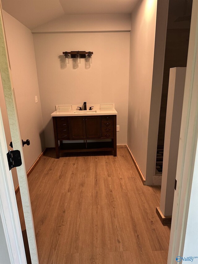 bathroom featuring hardwood / wood-style flooring, vanity, and lofted ceiling