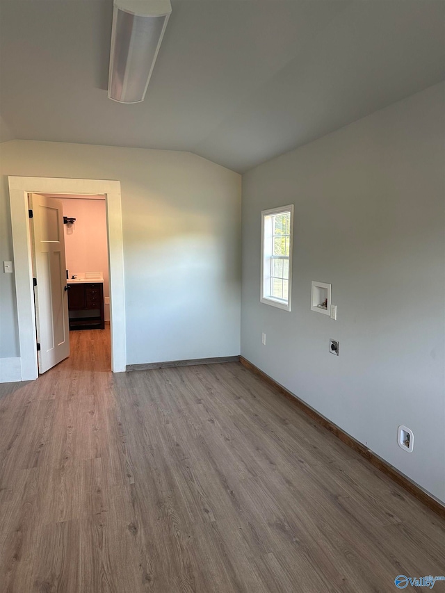 empty room featuring vaulted ceiling and hardwood / wood-style flooring