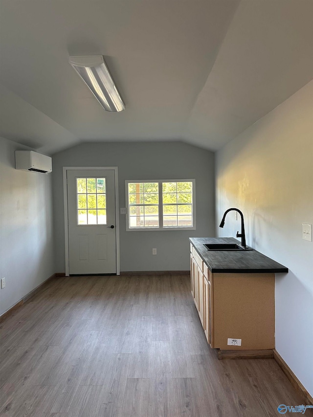 kitchen featuring vaulted ceiling, sink, a wall mounted air conditioner, and hardwood / wood-style flooring